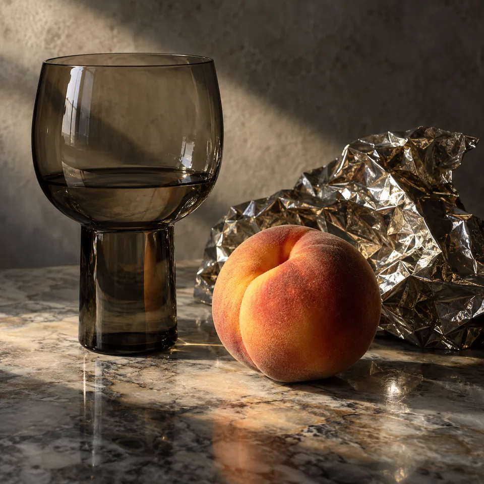 A still life of smoked glass, crumpled foil and a ripe peach, highly realistic material study